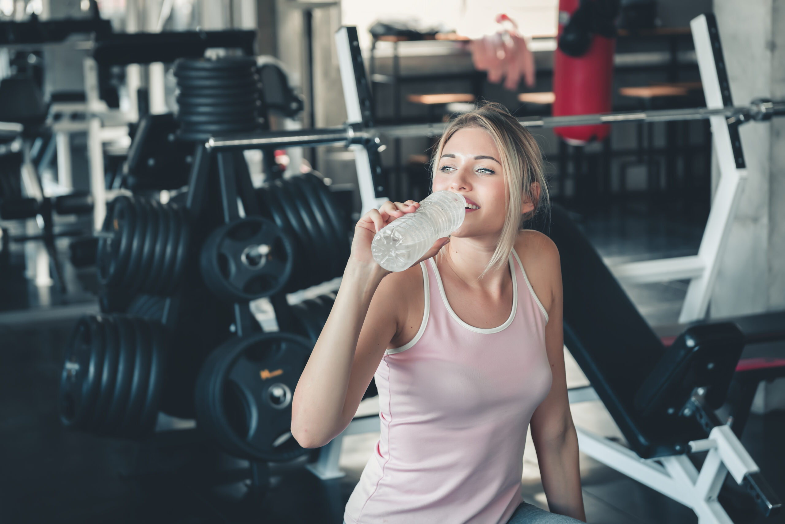 beautiful fitness woman is drinking water from bottle after work