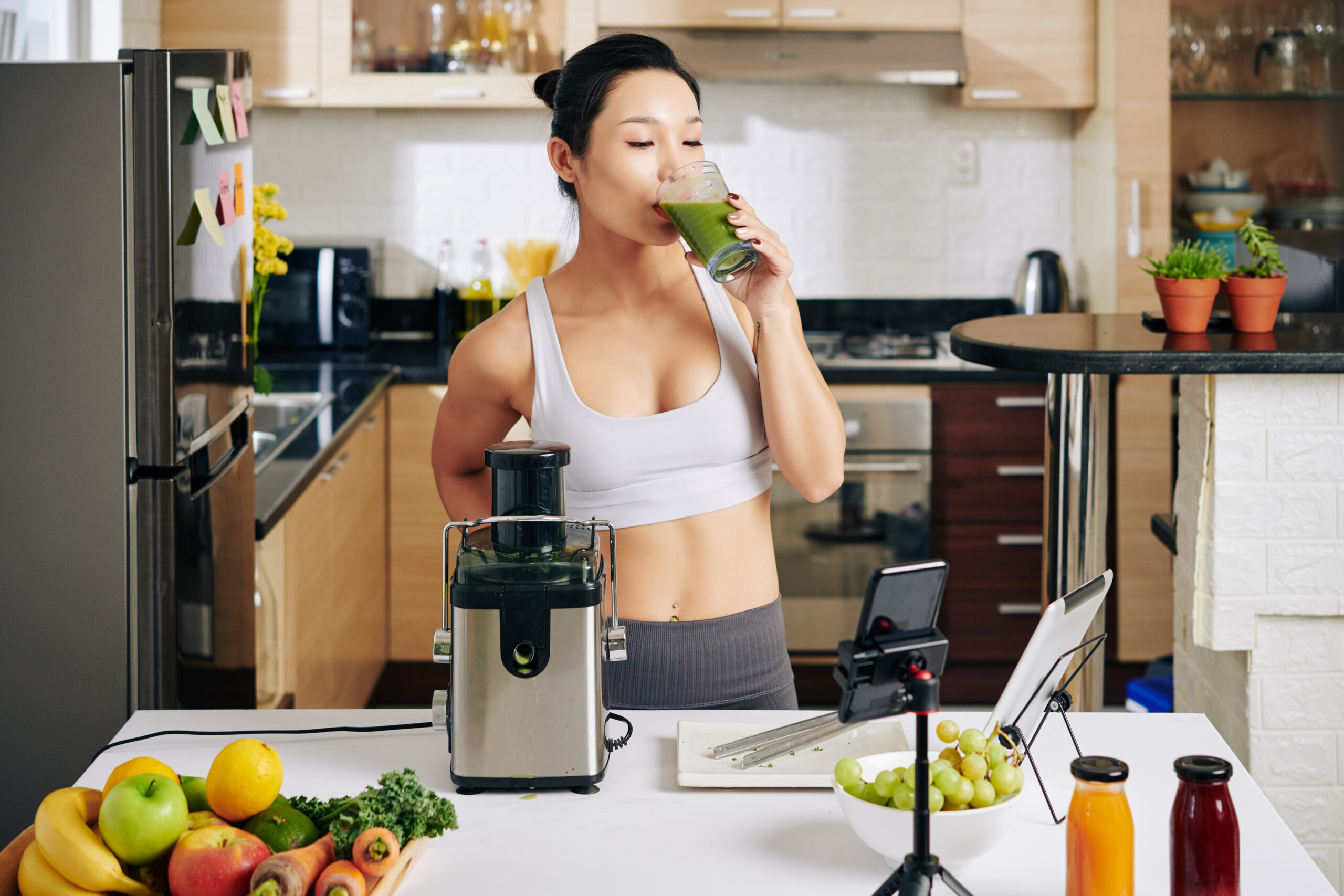 fit slim female athlete standing in kitchen and drinking glass o